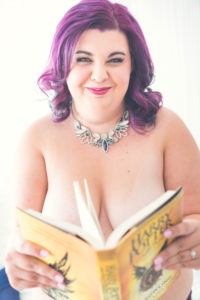 Woman with long purple hair and pink lipstick holds a Harry Potter book.