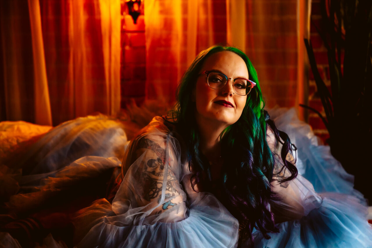 Woman with colorful hair posing for boudoir portrait in tulle robe