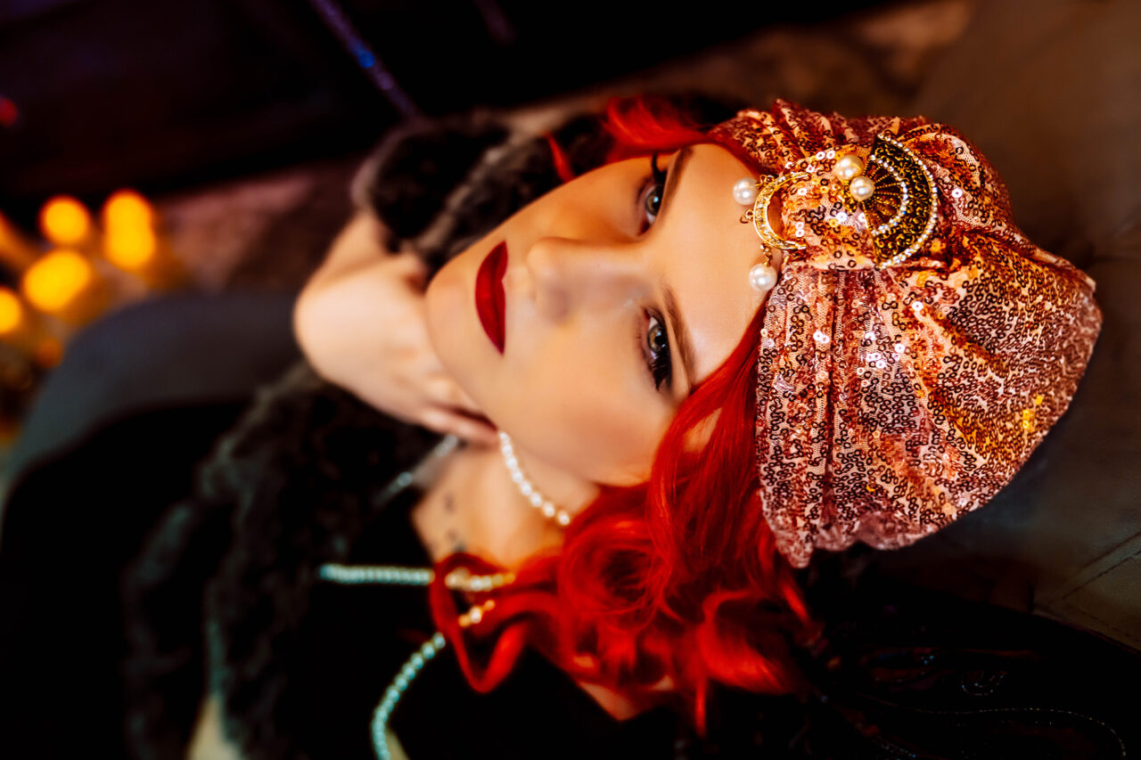 Red haired woman posing for boudoir portrait wearing unique headpiece
